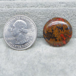 United States quarter dollar coin next to a red and brown stone on a gray surface