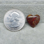 Heart-shaped Seam Agate stone next to a U.S. quarter dollar on a gray surface