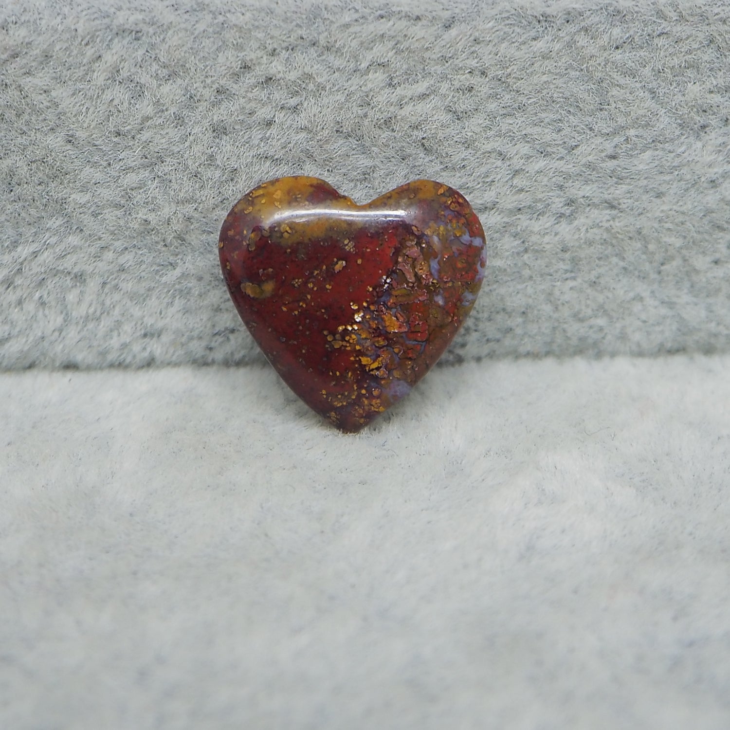 Heart-shaped amber stone on a textured gray surface