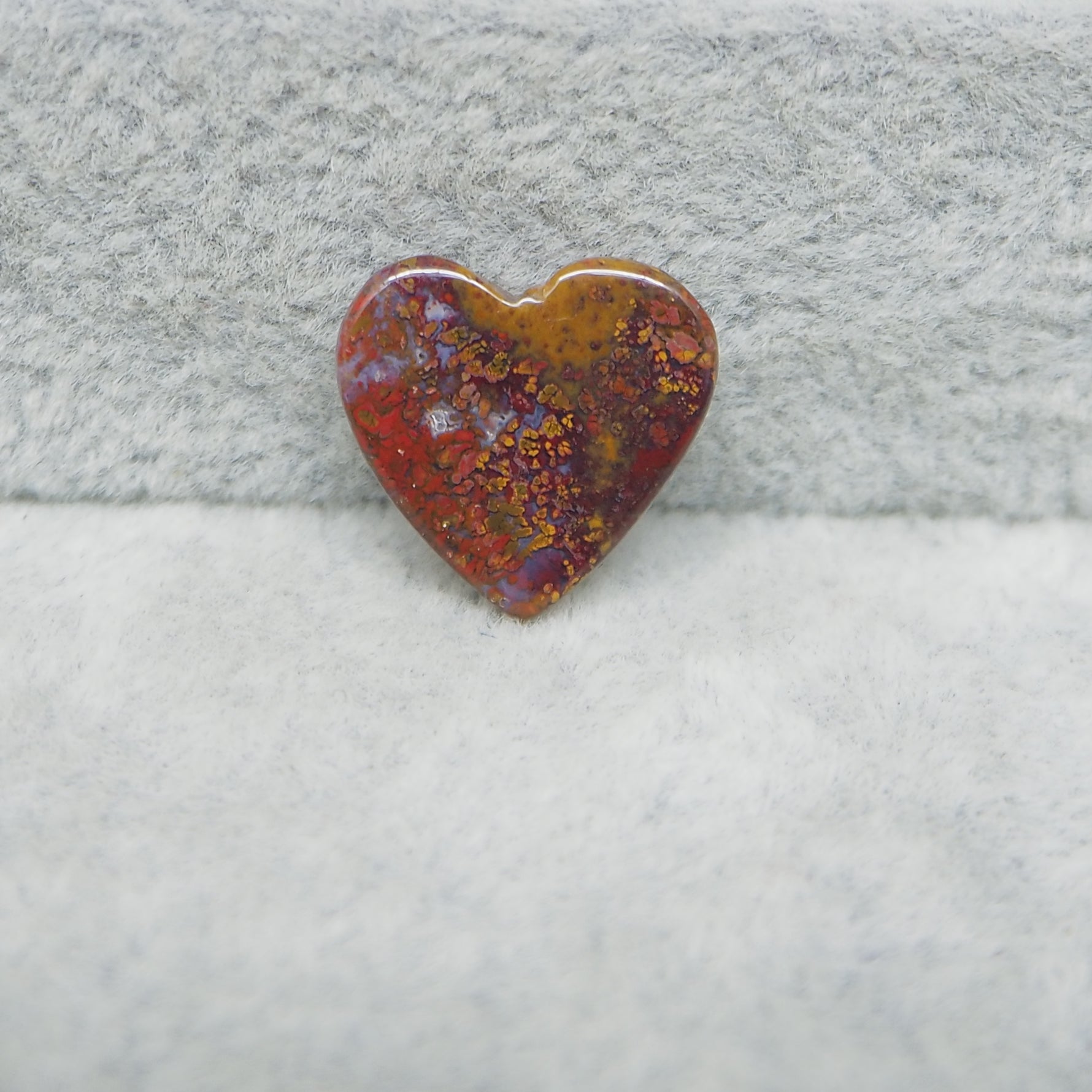 Heart-shaped stone with a textured surface on a gray fabric background
