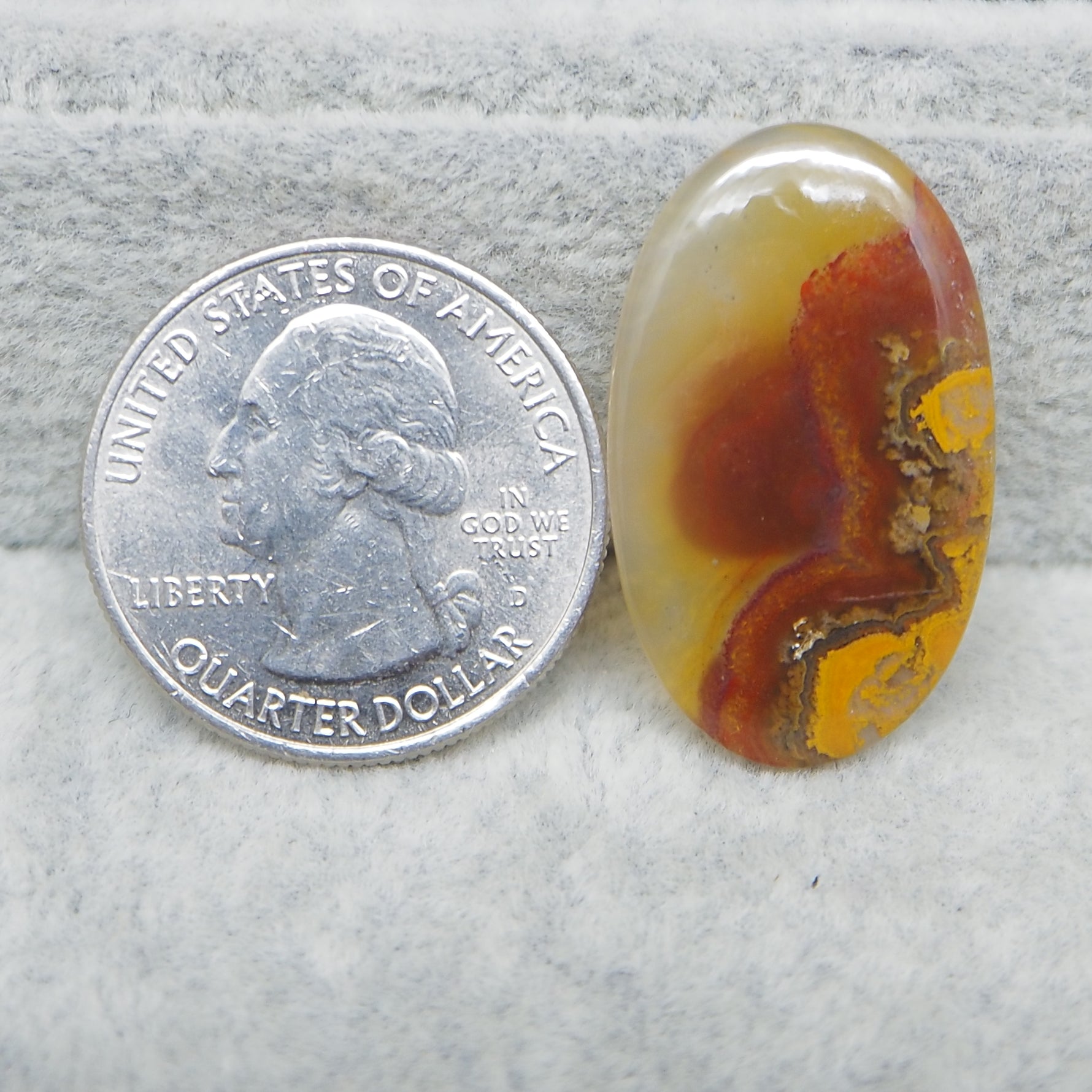 Agate stone next to a U.S. quarter dollar coin on a gray background