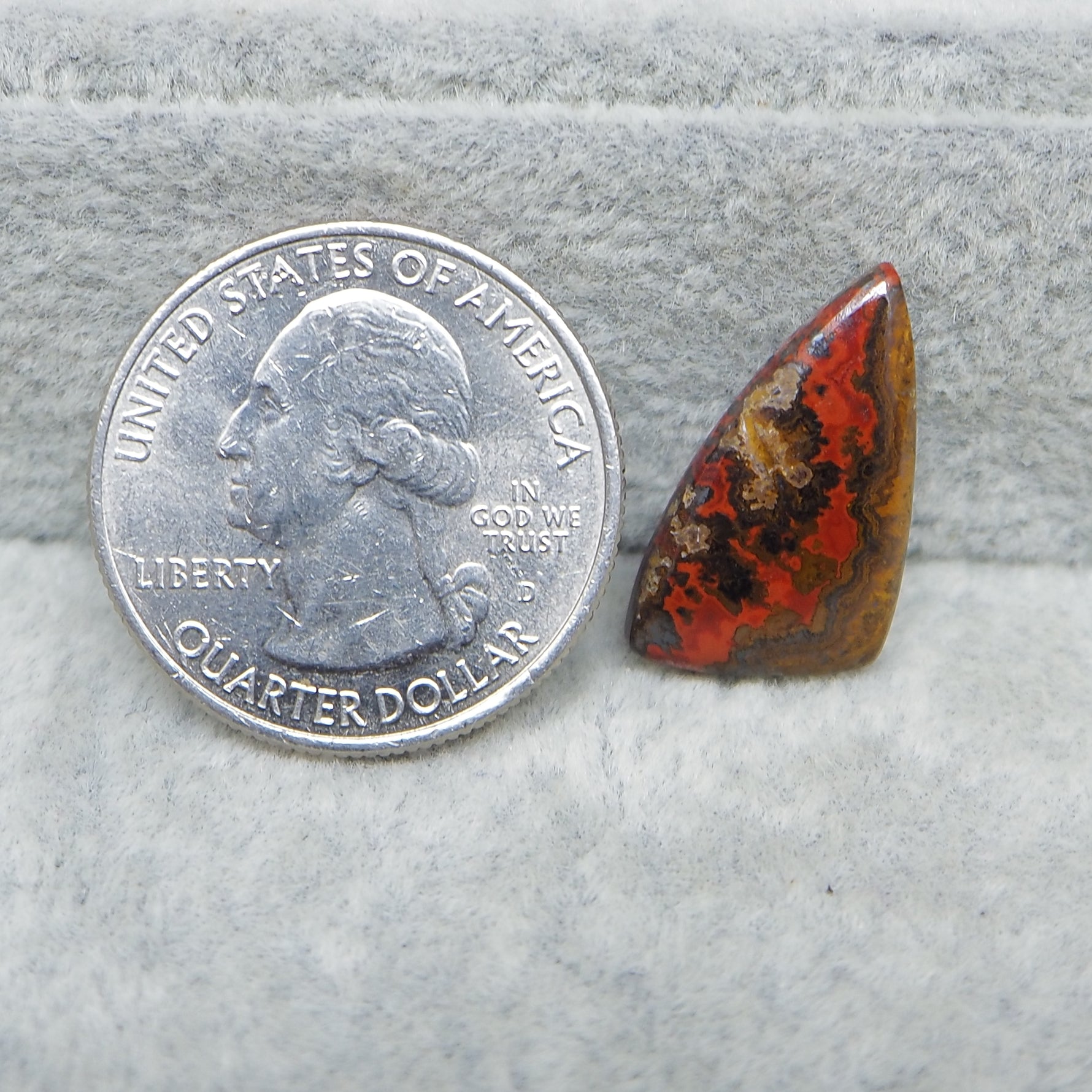 Quarter dollar coin next to a colorful stone on a textured surface