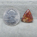 Quarter dollar coin next to a colorful triangular stone on a gray surface
