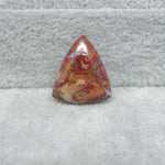 Triangular red and orange stone on a gray surface