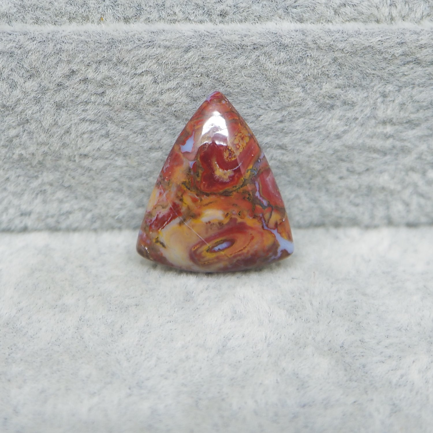 Triangular red and orange stone on a gray surface