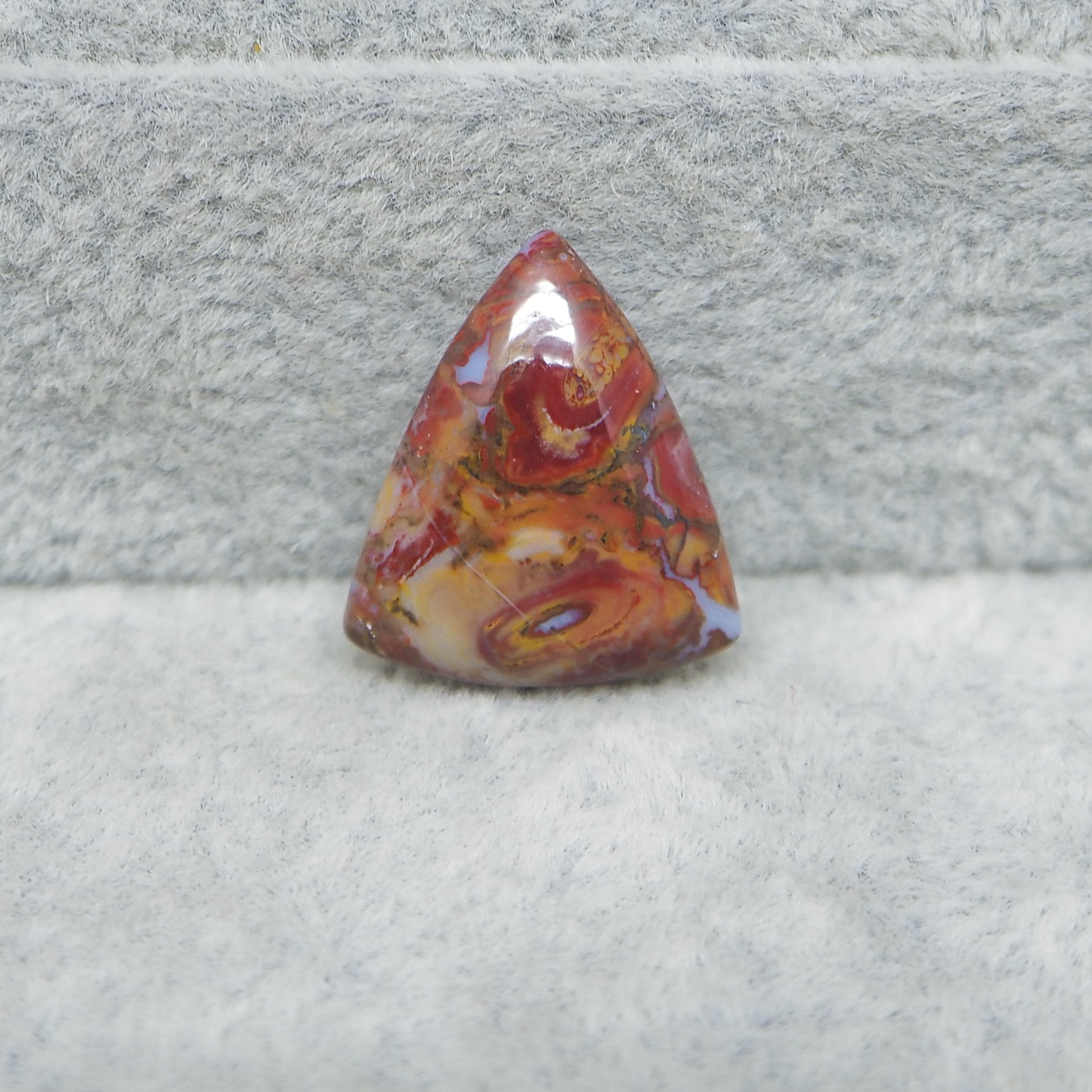 Triangular red and orange stone on a gray surface