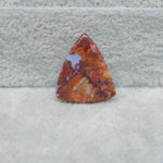 Triangular orange and red stone on a textured gray surface