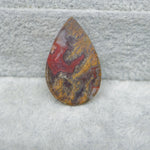 Teardrop-shaped jasper stone on a gray surface