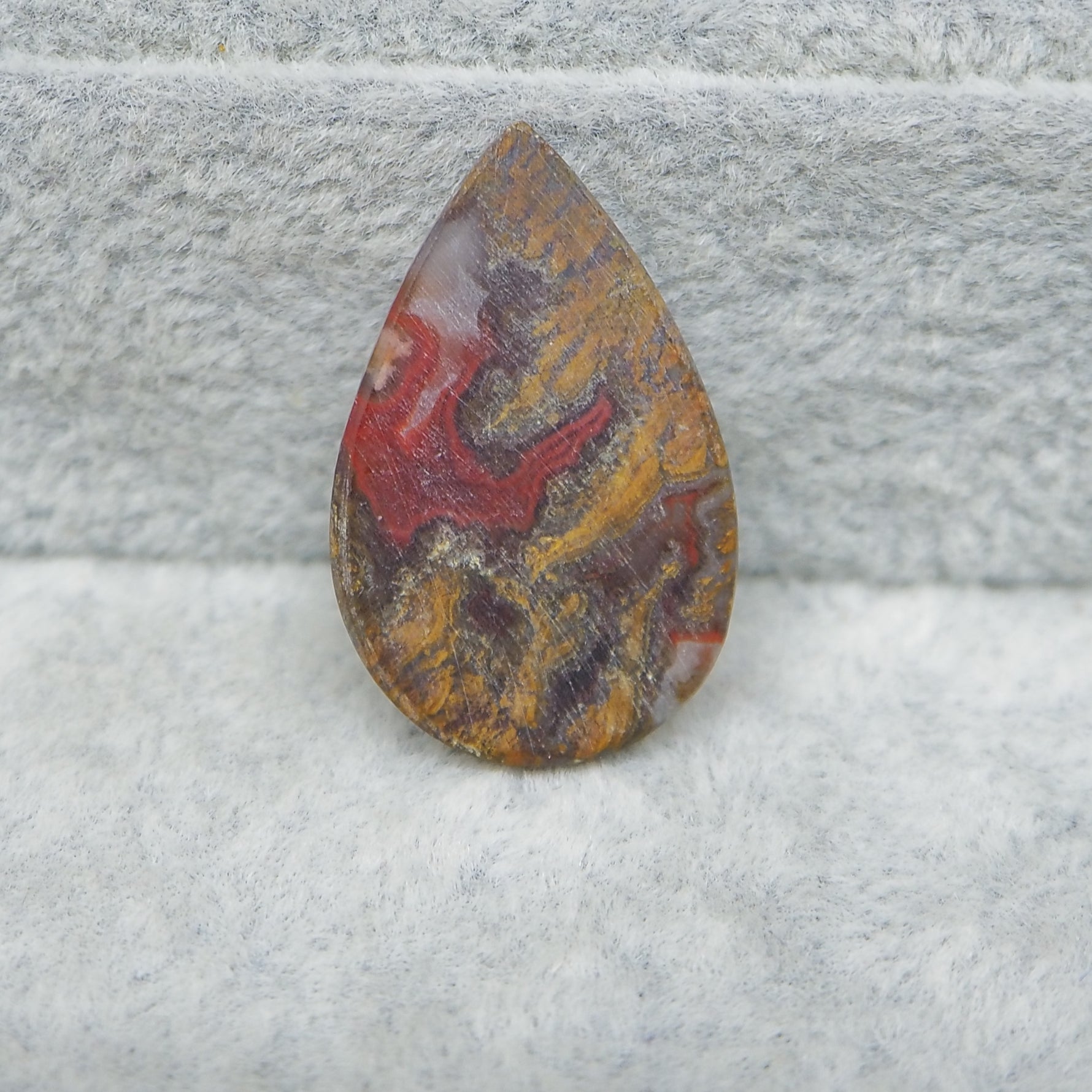Teardrop-shaped jasper stone on a gray surface