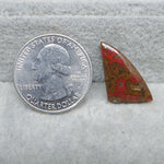 Quarter dollar coin next to a red and brown stone on a gray surface