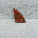Triangular red and brown stone on a textured gray surface
