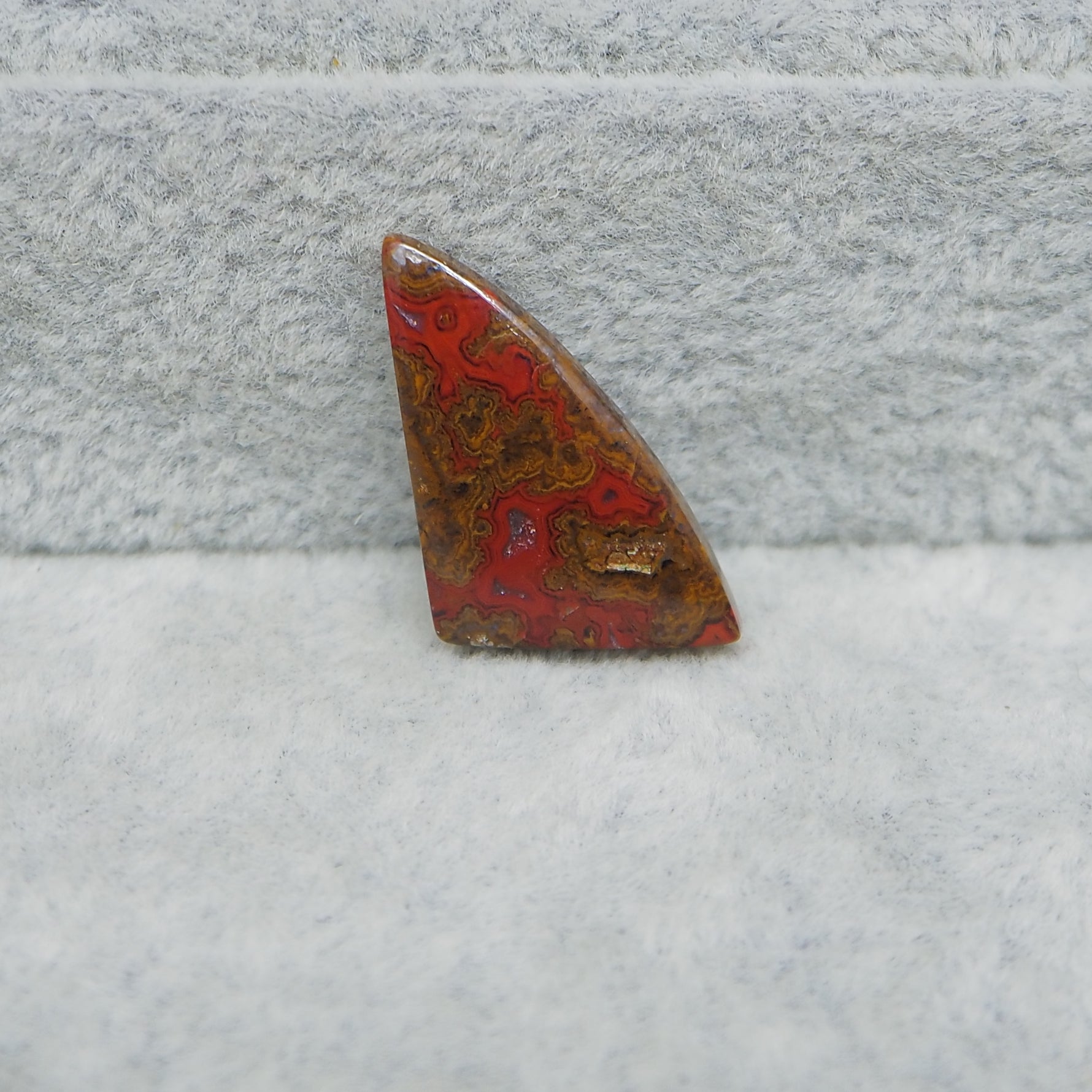 Triangular red and brown stone on a textured gray surface