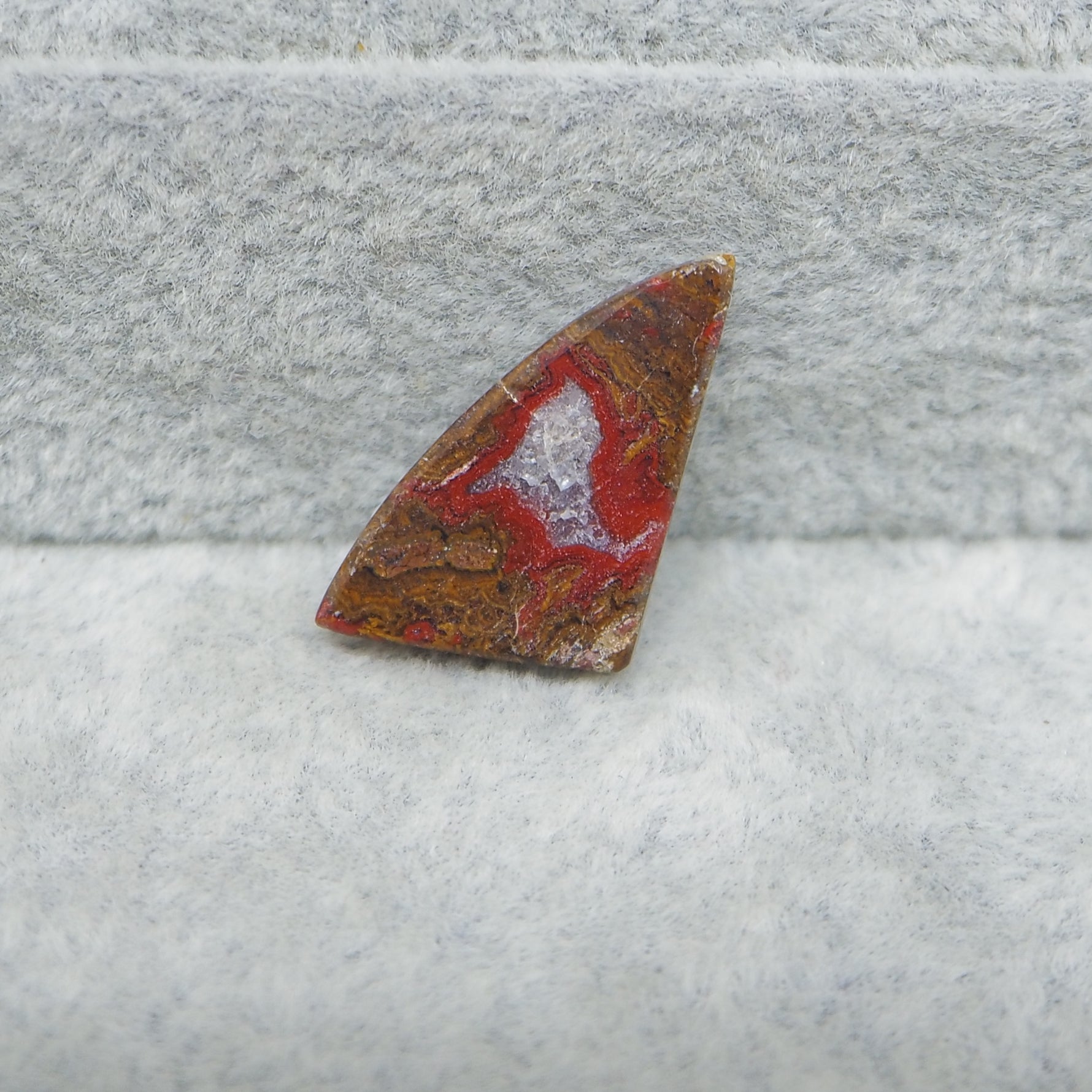 Polished stone with red and brown patterns on a gray surface