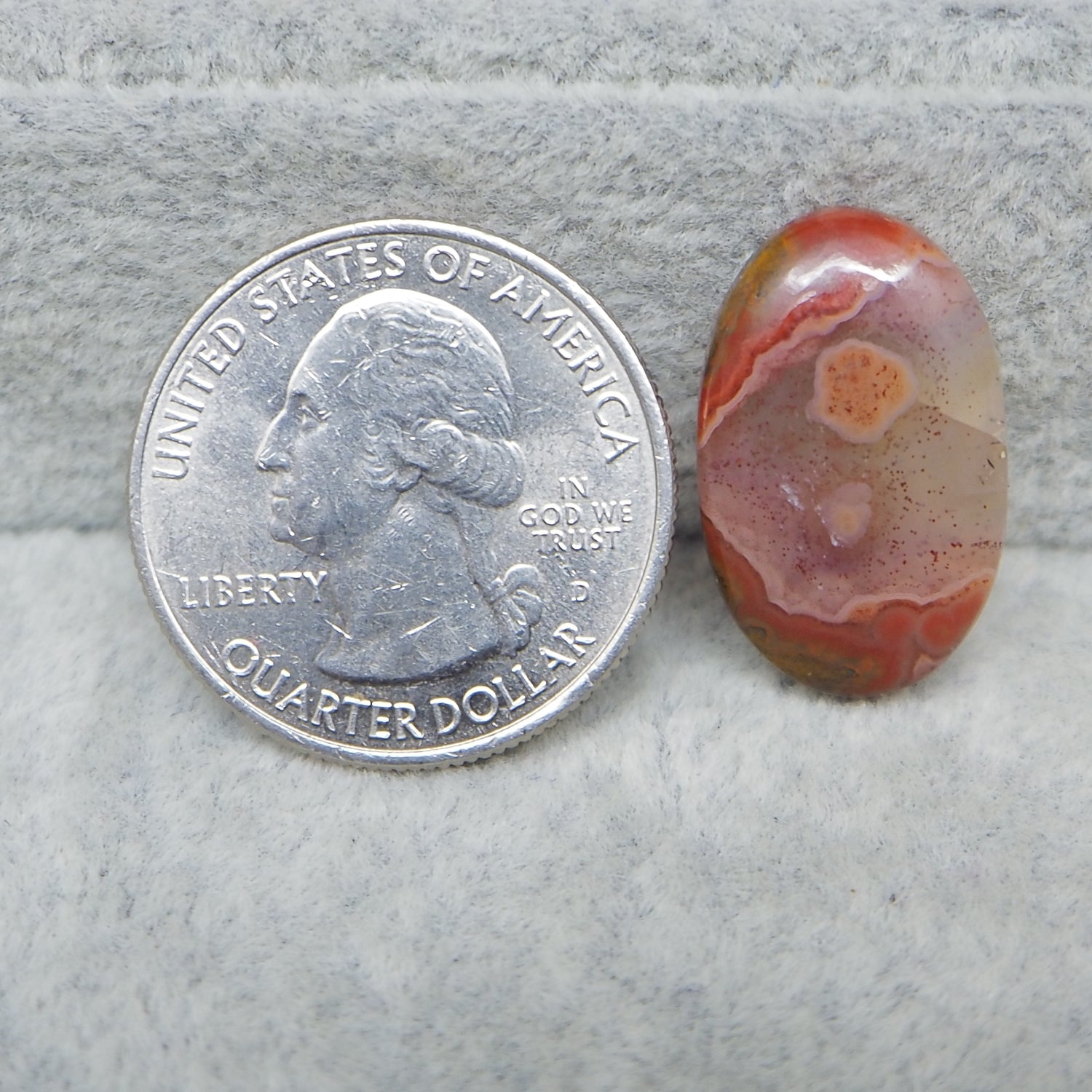Quarter dollar coin next to a colorful stone on a gray surface