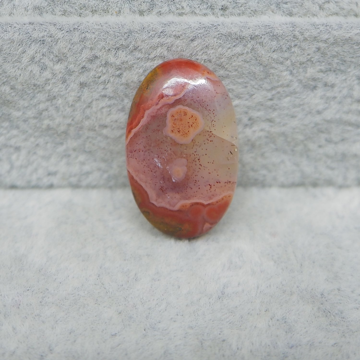 Oval-shaped agate stone on a textured gray surface