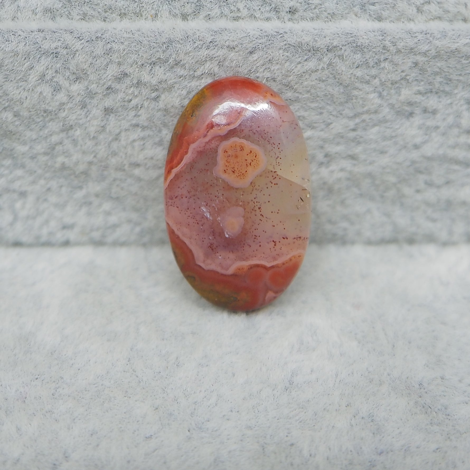 Oval-shaped agate stone on a textured gray surface