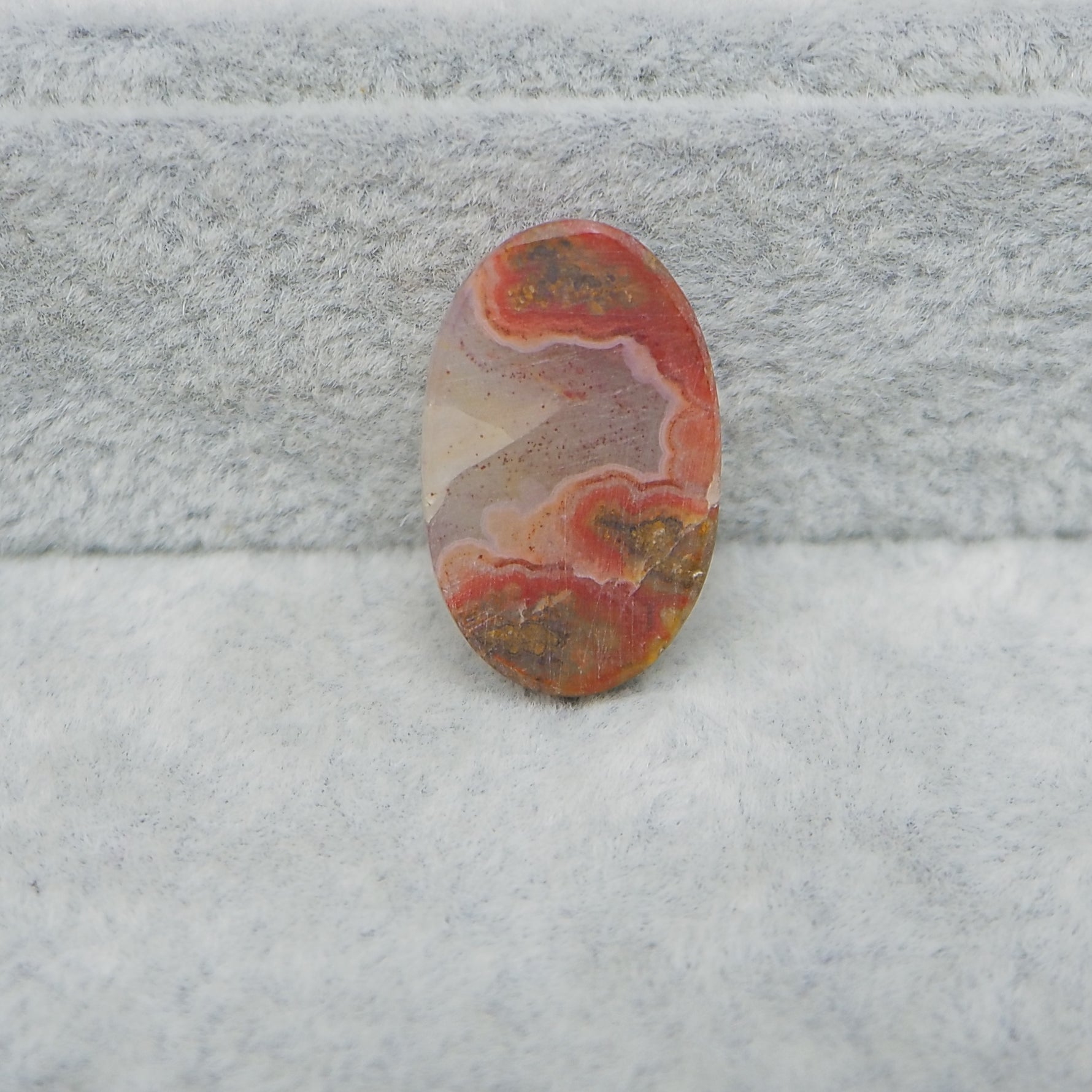Oval-shaped multicolored stone on a textured gray surface