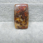 Rectangular stone with brown, orange, and yellow patterns on a gray surface