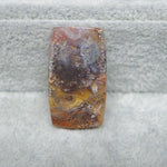 Rectangular stone with brown and white patterns on a textured gray background
