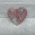 Heart-shaped stone with a textured surface on a gray stone background