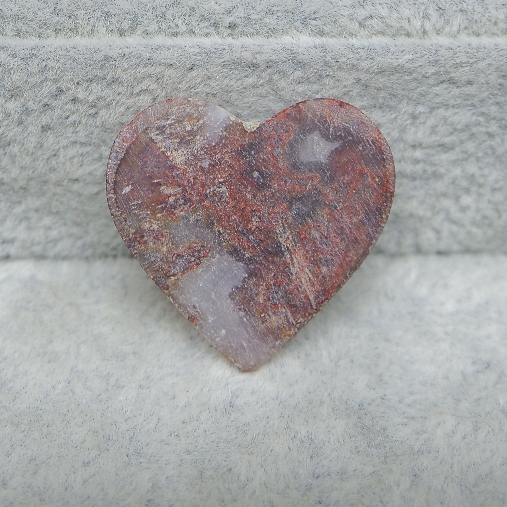 Heart-shaped stone with a textured surface on a gray stone background