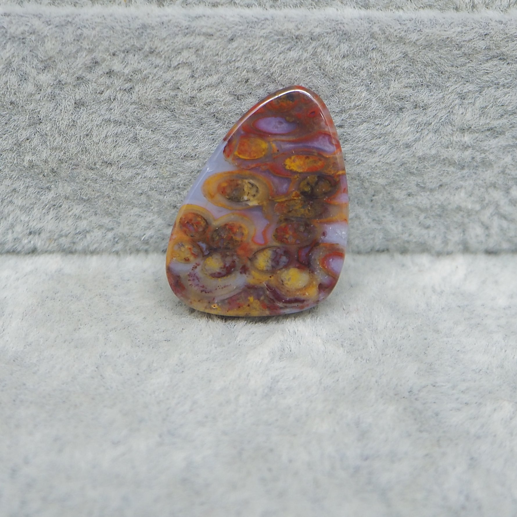Marbled stone with orange, yellow, and purple colors on a textured gray background