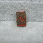 Rectangular stone with red and brown patterns on a gray textured background