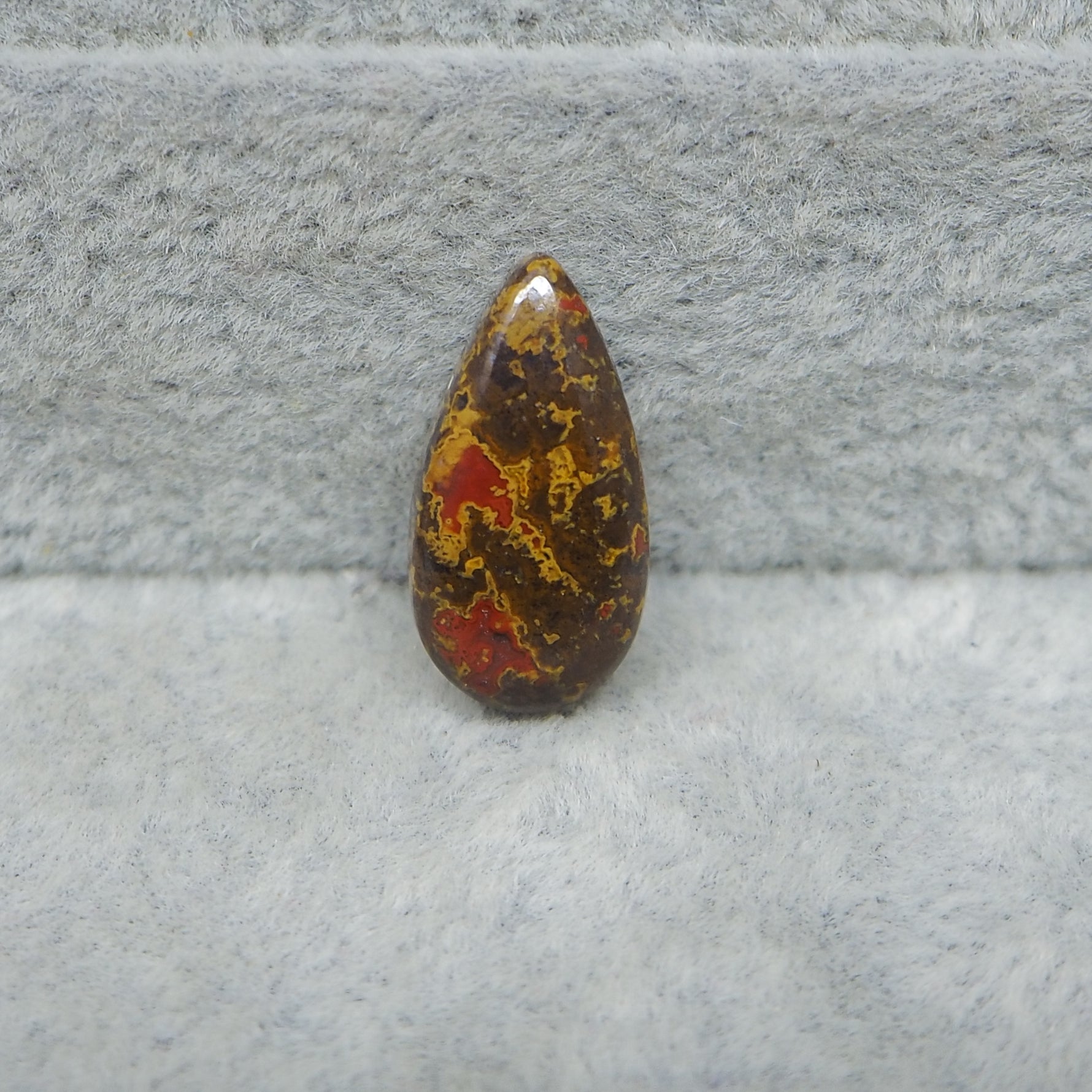 Polished stone with red and yellow patterns on a gray surface