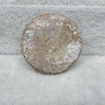 Round metal object with text on a textured gray surface