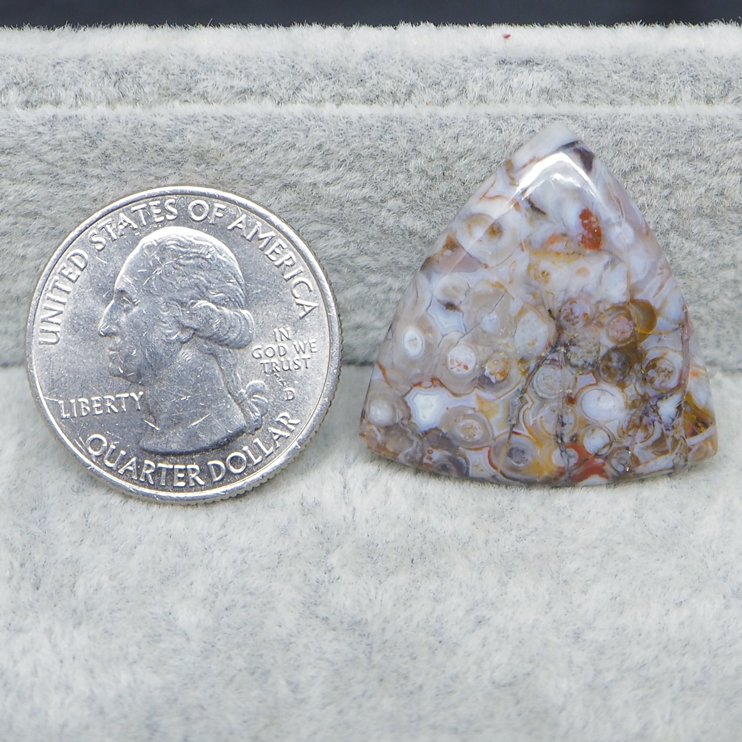 Agate stone next to a U.S. quarter dollar on a white background