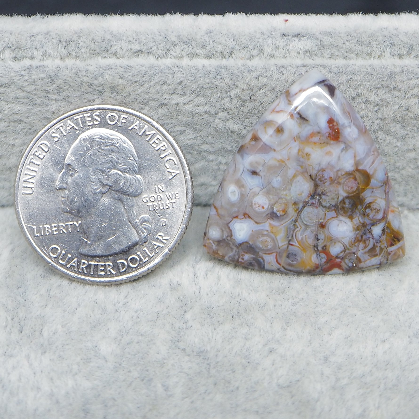 Agate stone next to a U.S. quarter dollar on a white background