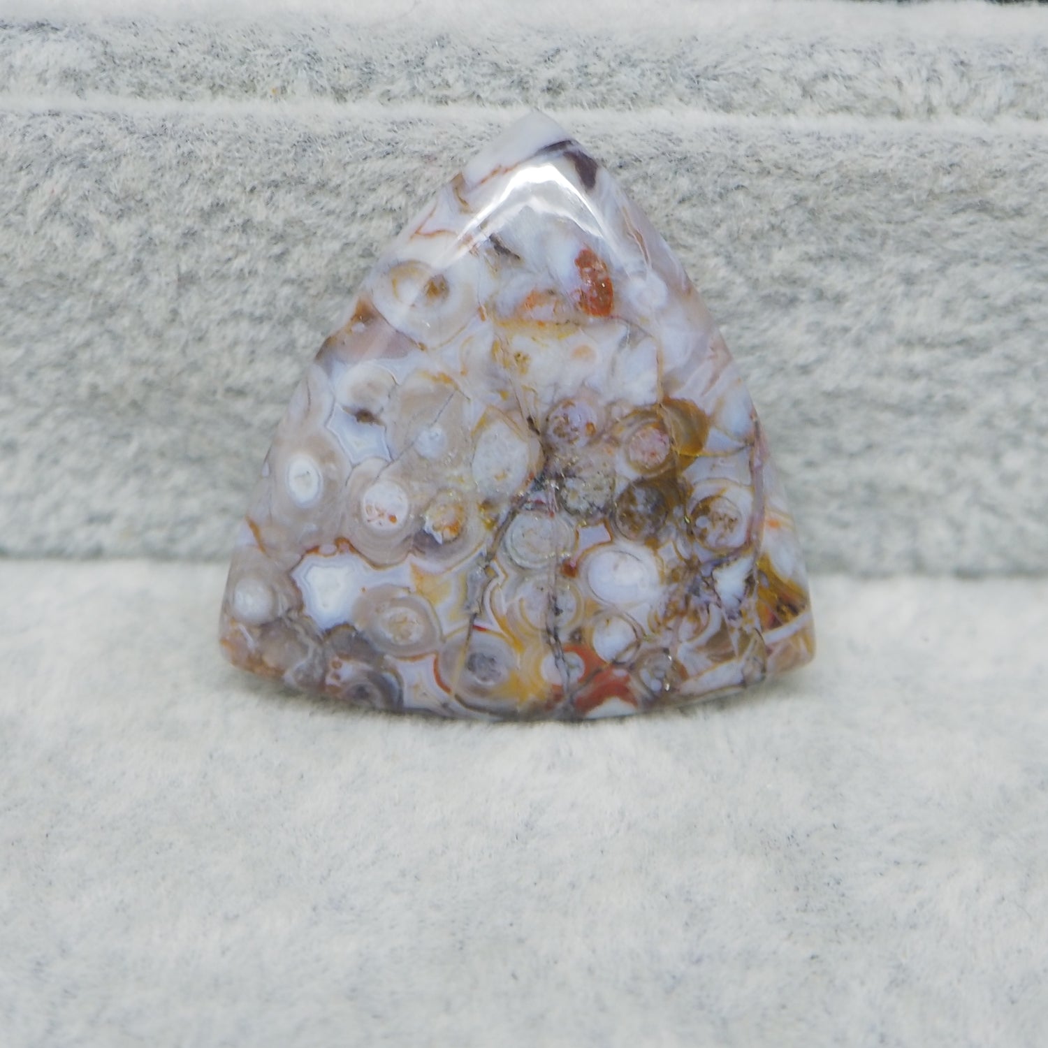 Polished piece of agate with a multicolored pattern on a textured surface