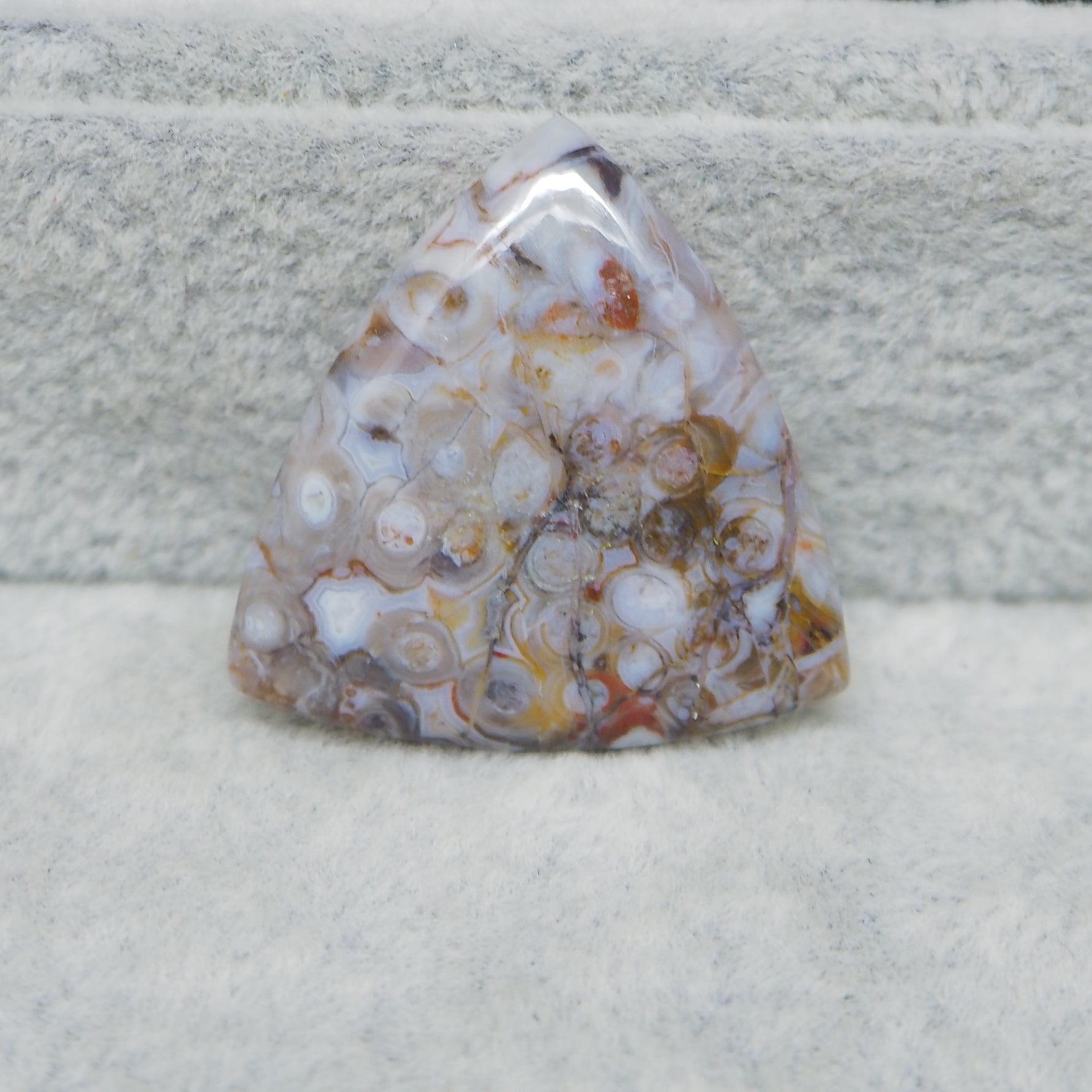 Polished piece of agate with a multicolored pattern on a textured surface