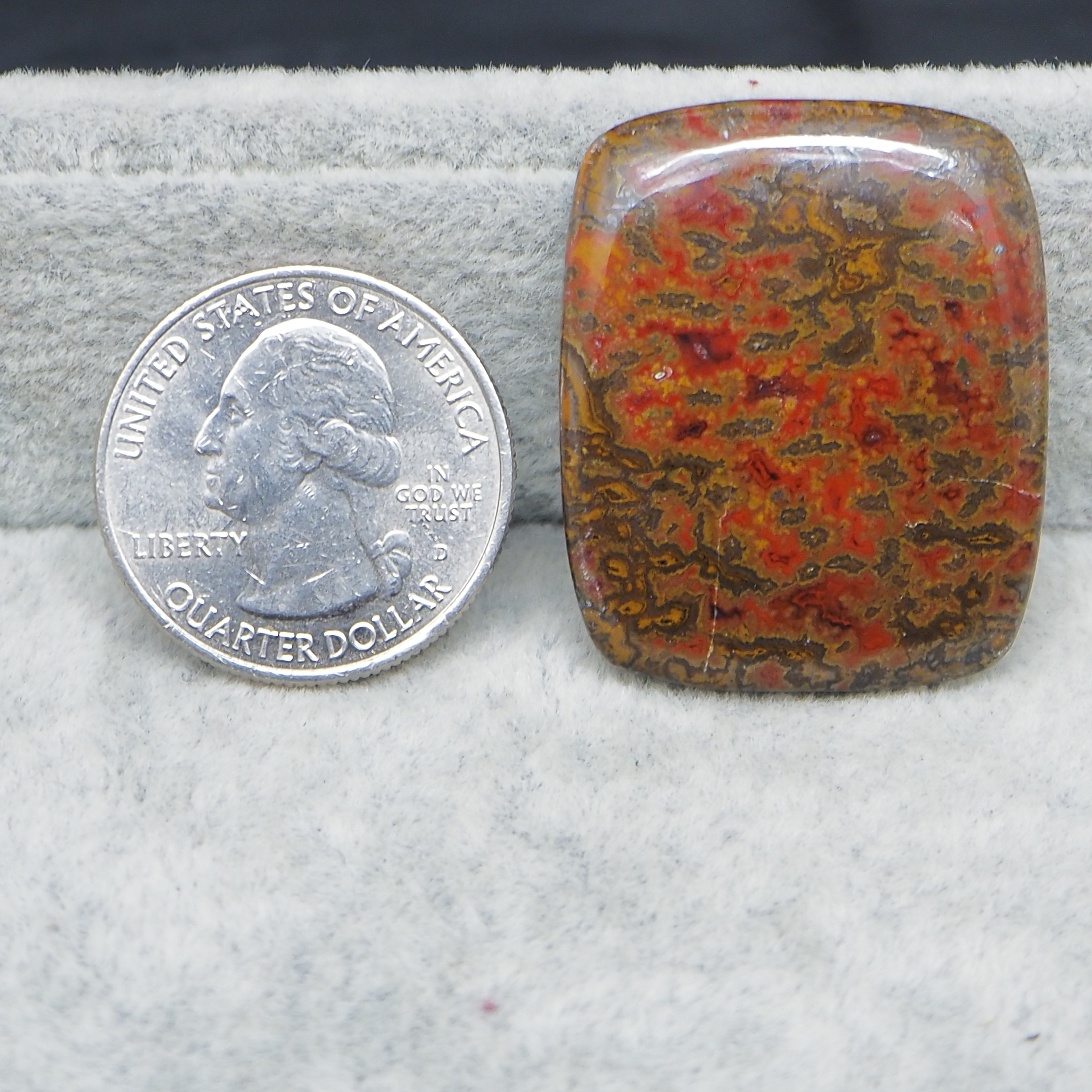 Patterned stone next to a U.S. quarter dollar on a gray surface