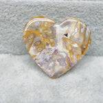 Heart-shaped stone with gold and white patterns on a gray background