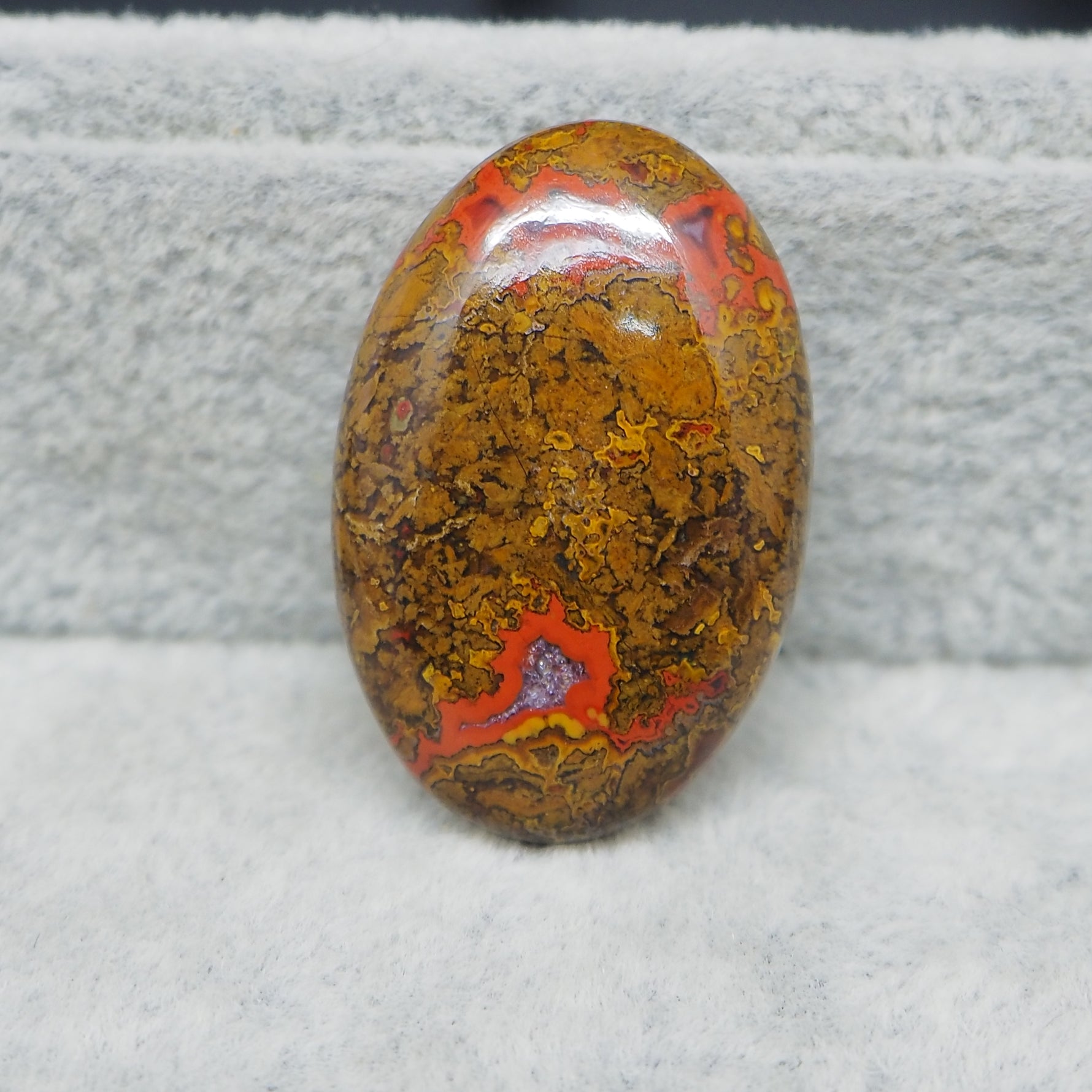 Oval-shaped multicolored stone on a textured gray background