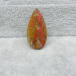 Polished stone with red and brown patterns on a textured gray surface