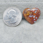 Heart-shaped agate stone next to a U.S. quarter dollar coin on a gray surface