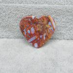 Heart-shaped stone with a marbled pattern on a textured surface