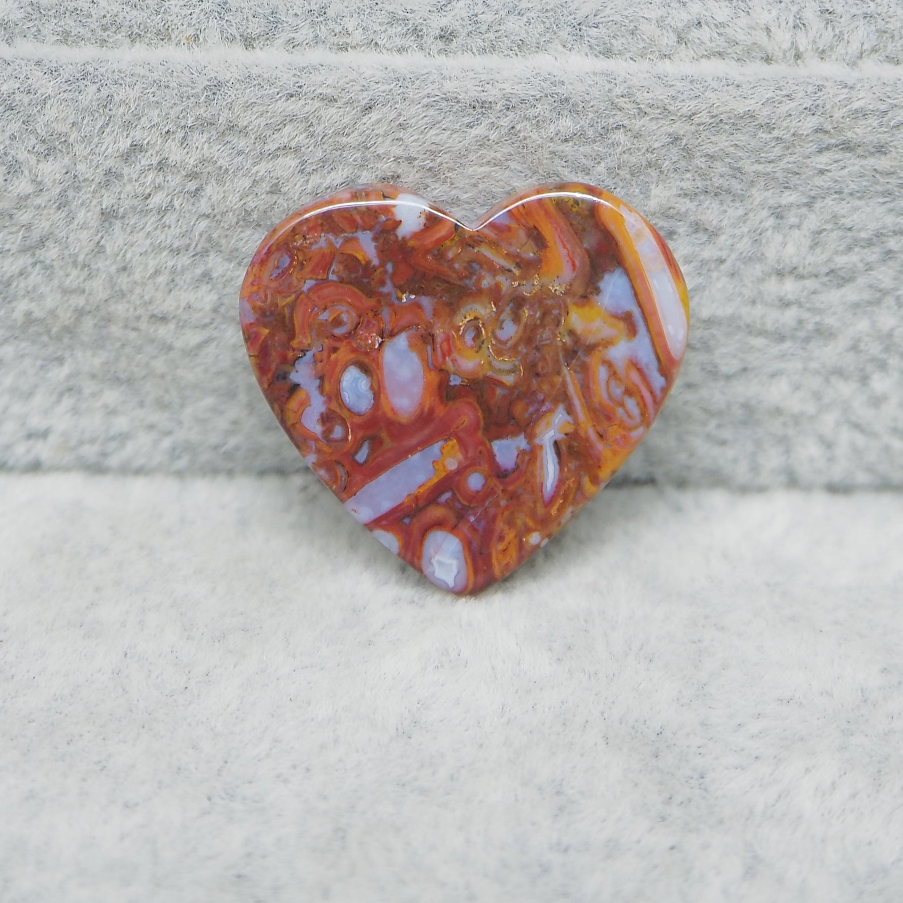 Heart-shaped stone with a marbled pattern on a textured surface