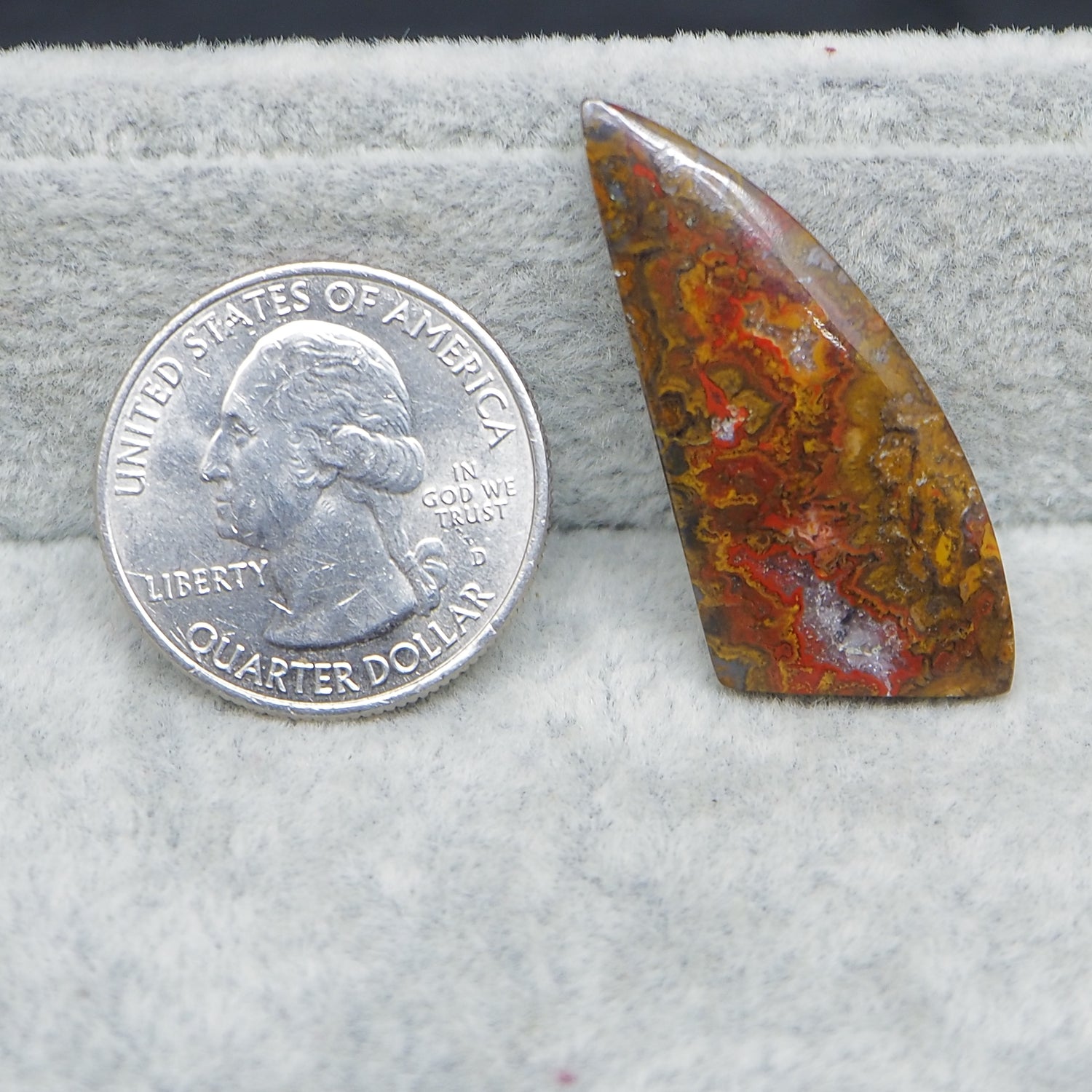 Polished stone next to a U.S. quarter dollar on a gray background