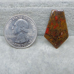 Quarter dollar coin next to a red and brown stone on a gray surface