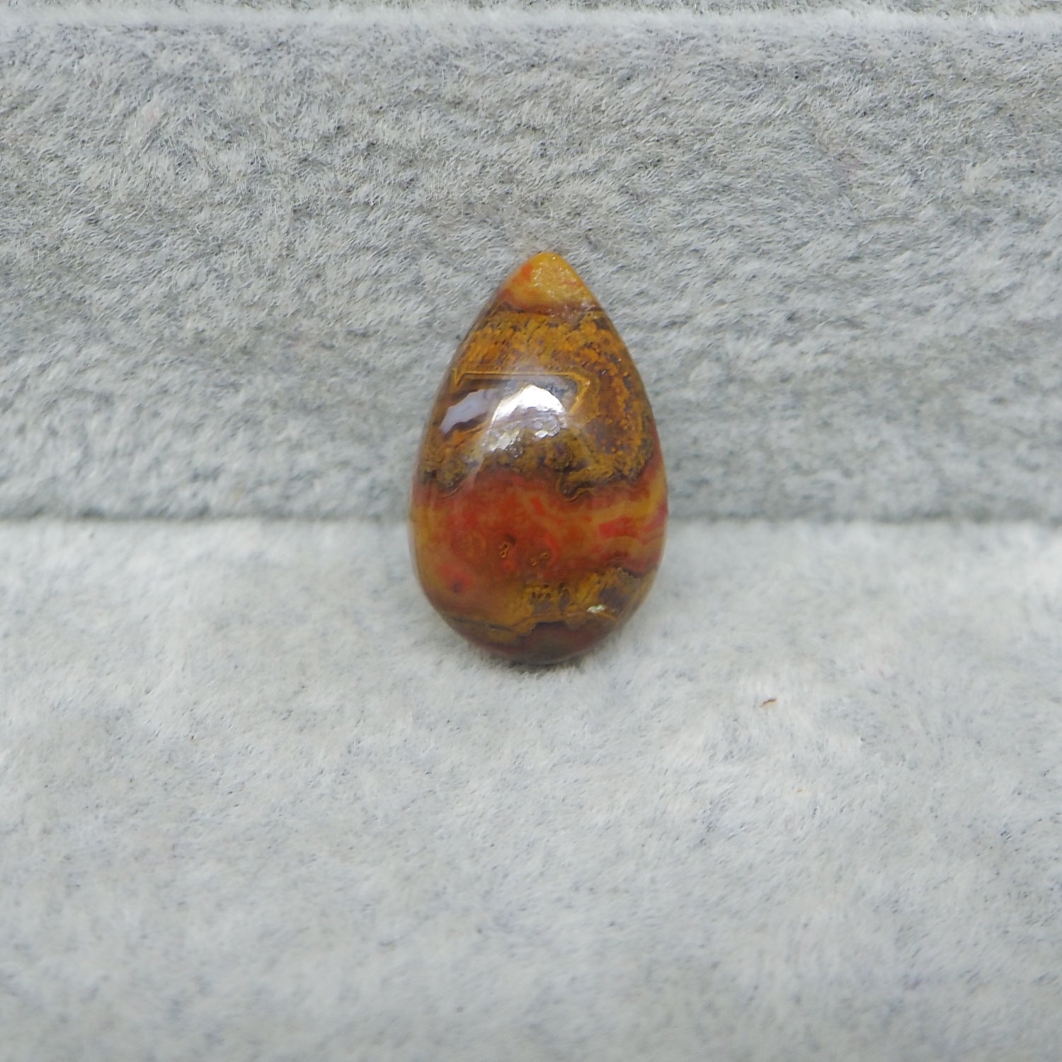 Teardrop-shaped amber stone on a gray surface