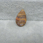 Teardrop-shaped amber stone on a gray fabric background