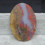 Oval-shaped stone with multicolored patterns on a textured surface