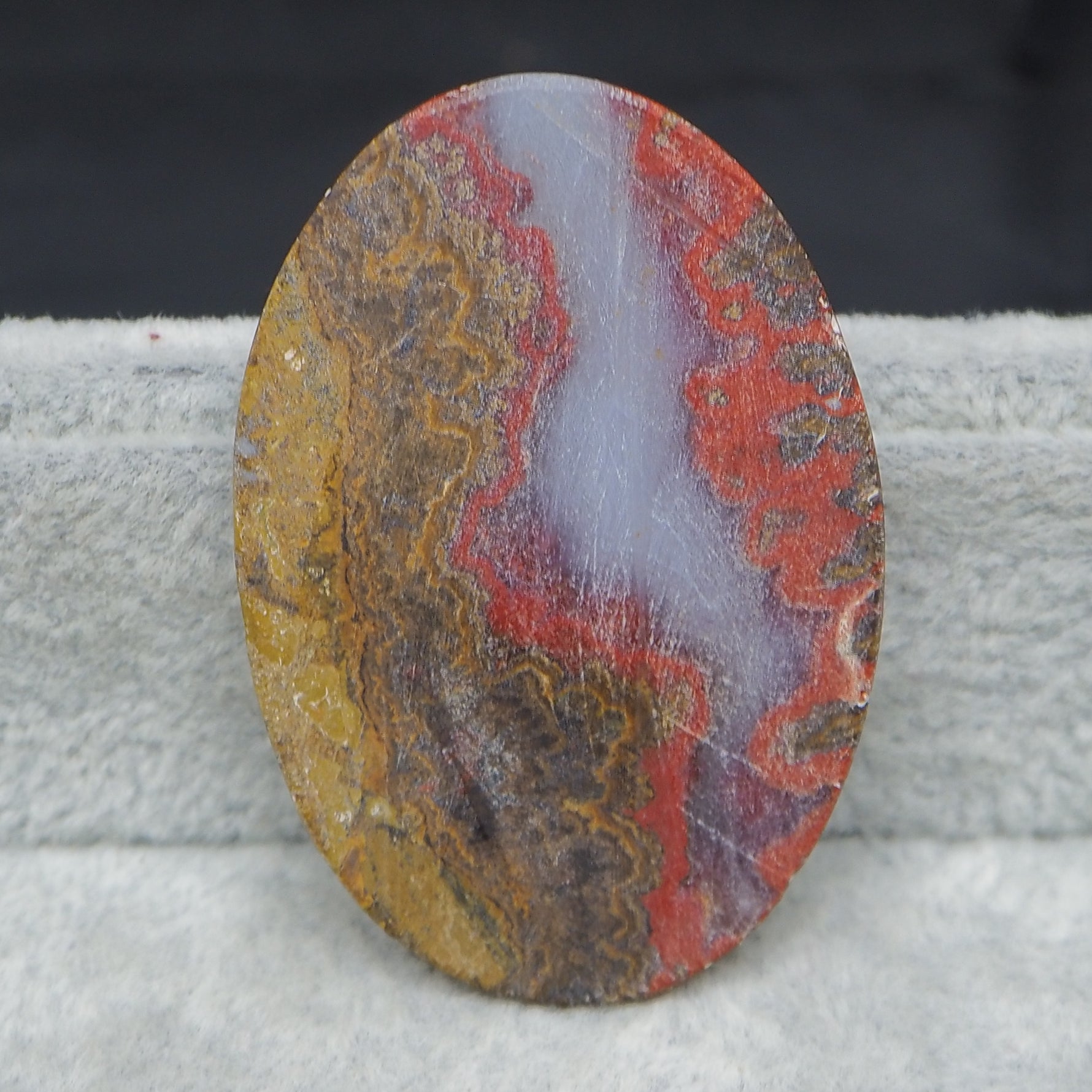 Oval-shaped stone with multicolored patterns on a textured surface