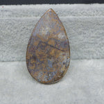 Teardrop-shaped stone with marbled pattern on a textured surface