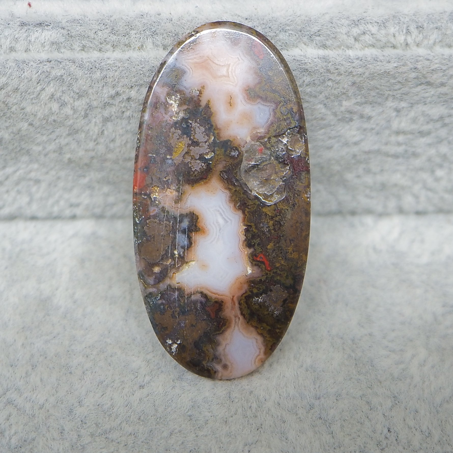 Oval-shaped agate stone on a textured gray background