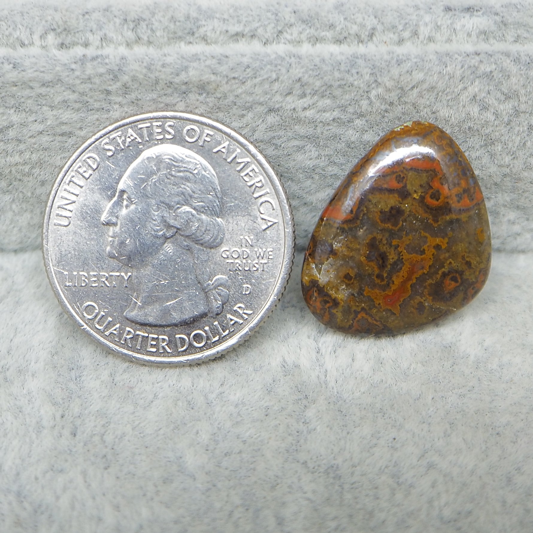 United States quarter dollar coin next to a brown and red patterned stone on a gray surface