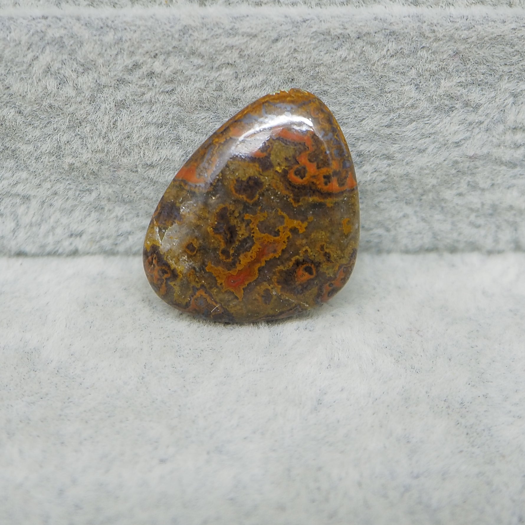 Polished stone with brown and red patterns on a gray surface